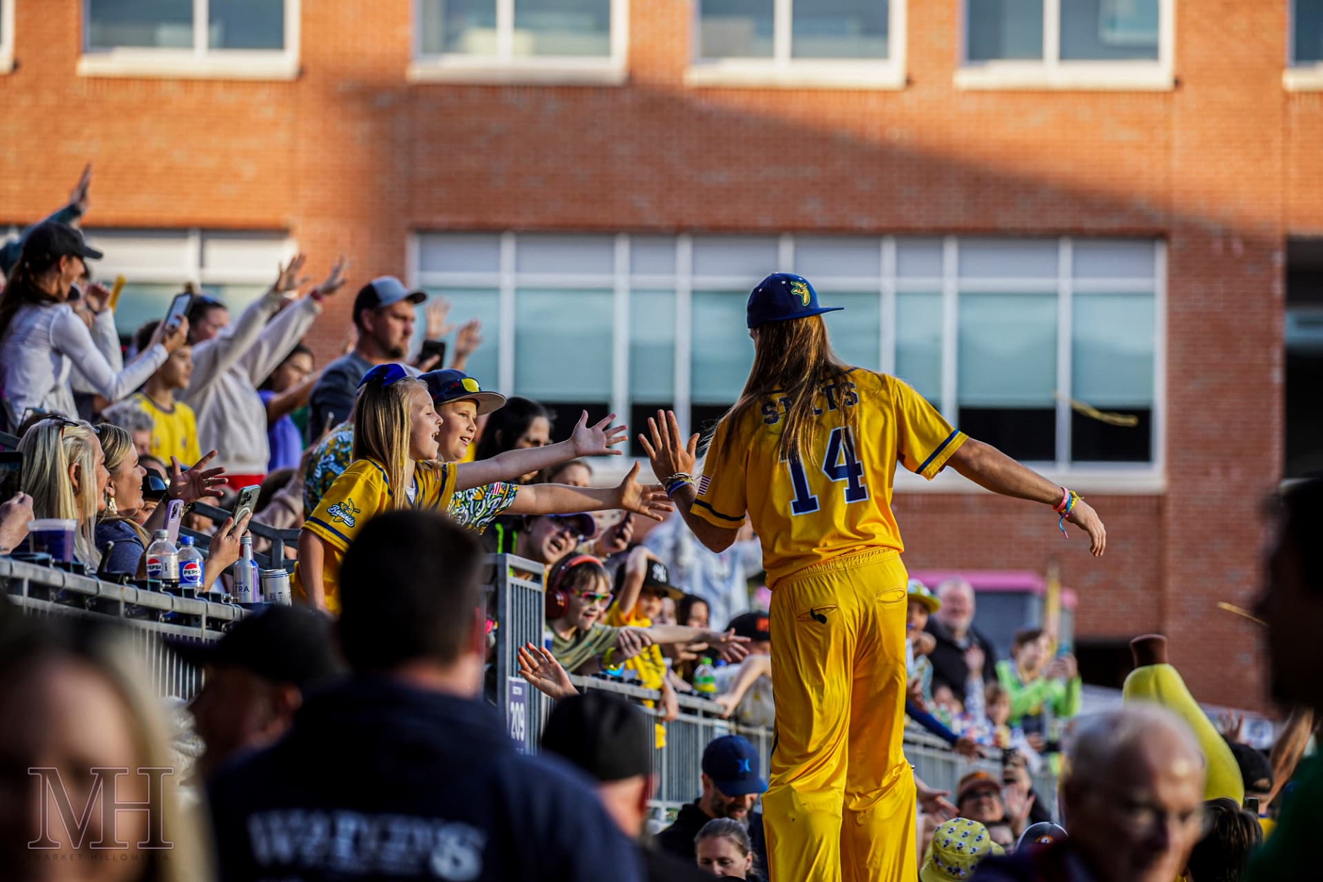 Player high-fiving young fans along the stadium rail