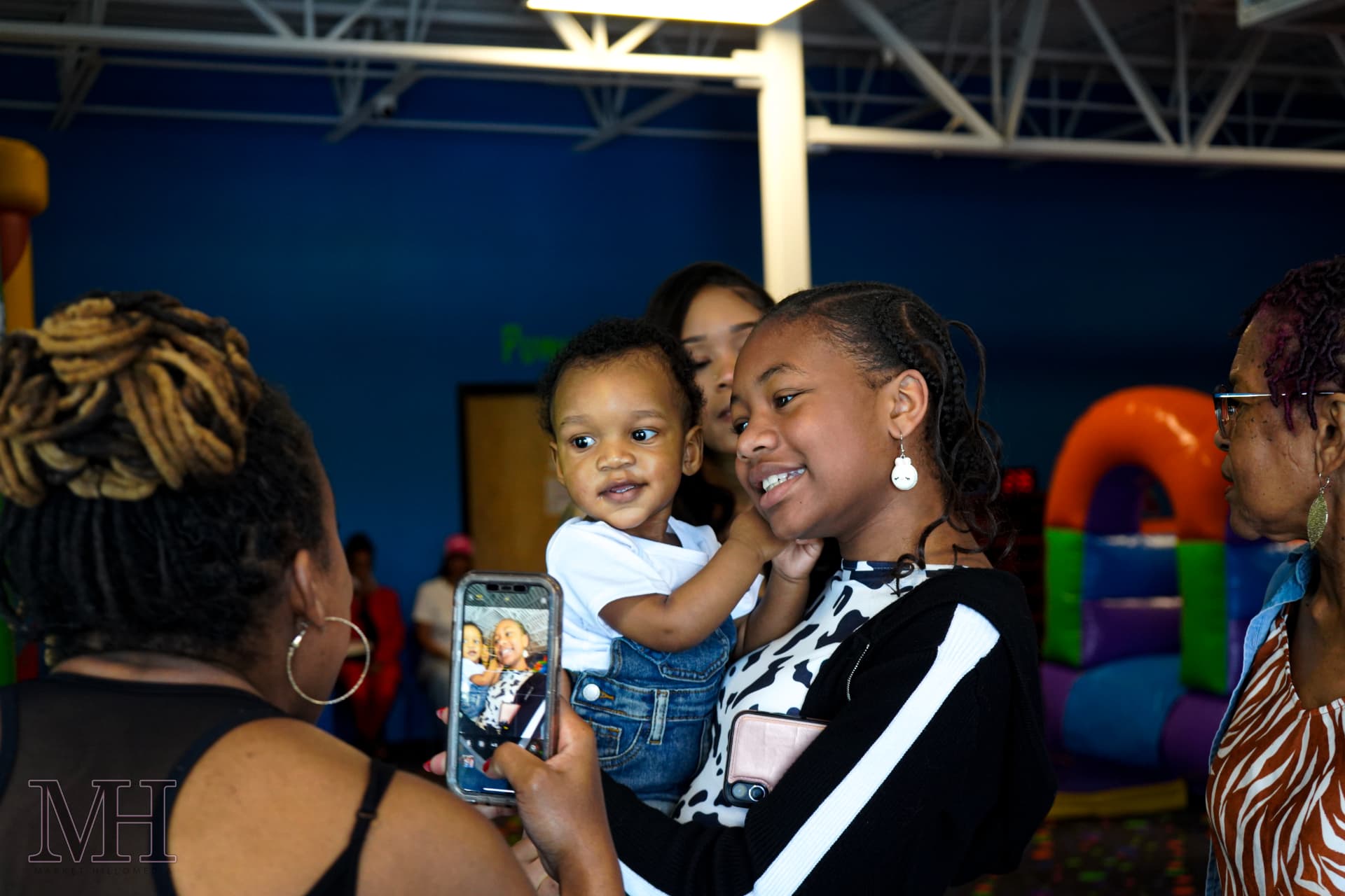 Family sharing a phone photo with a toddler at a birthday party