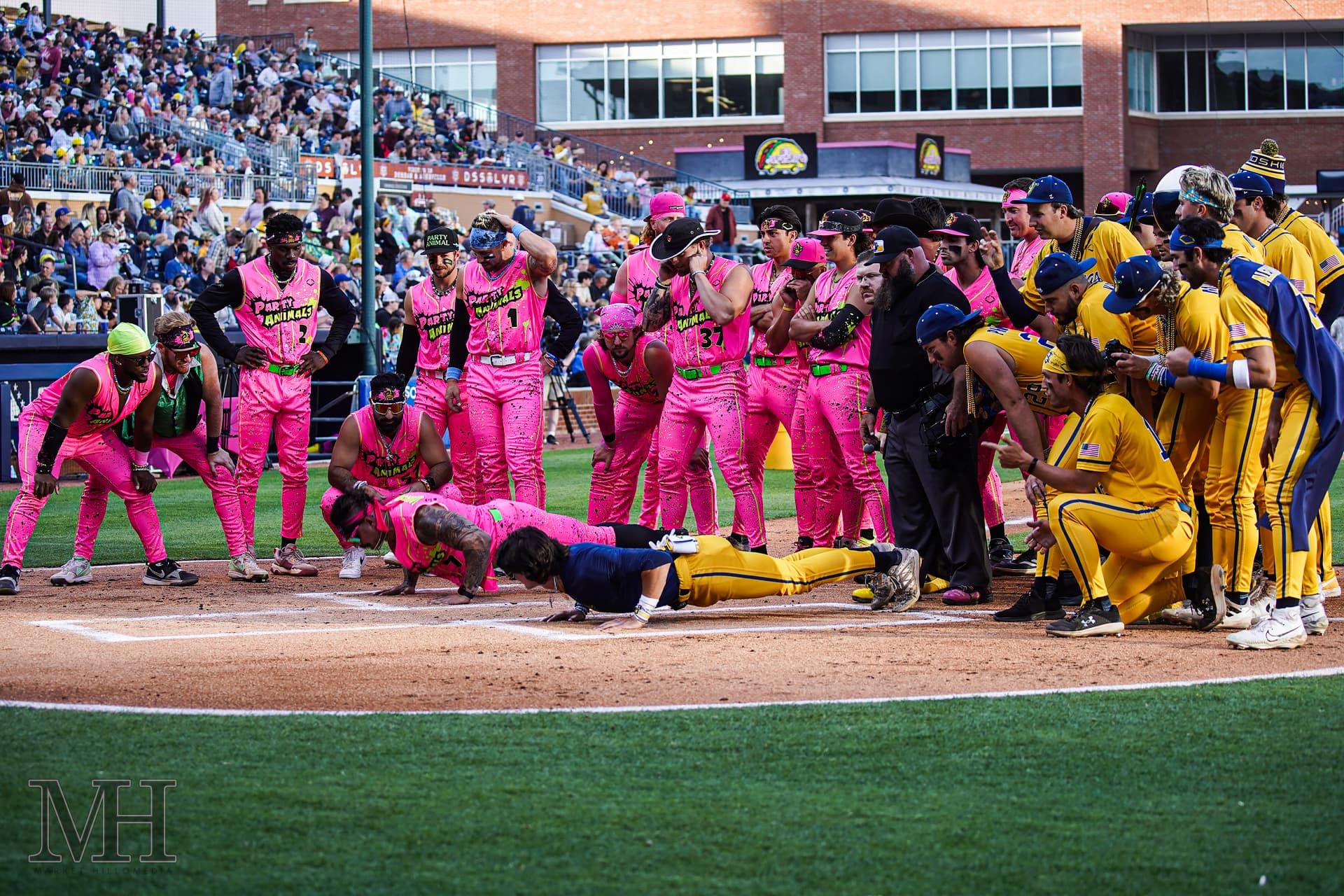 Players gathered at home plate during a live ballpark event