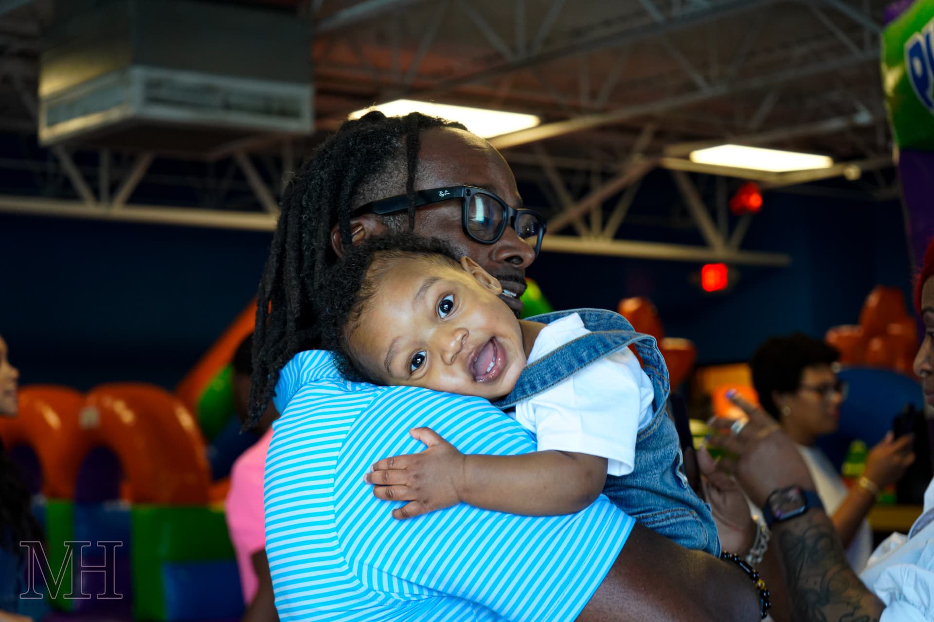 Father holding his smiling baby at a play-place celebration